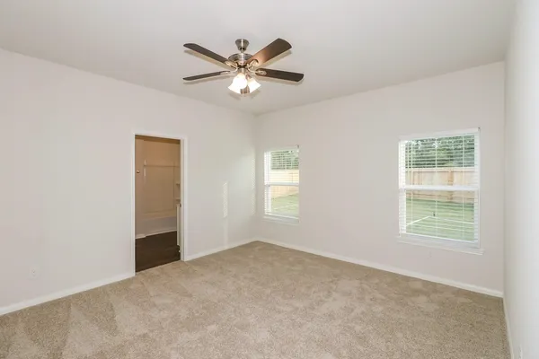 an empty room with windows and fan