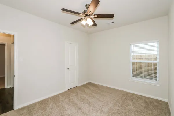 an empty room with windows and fan