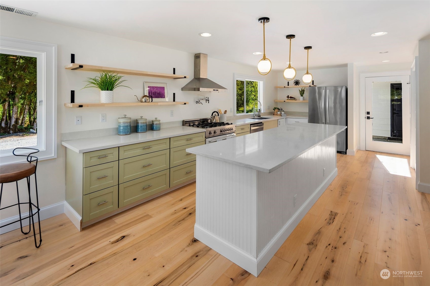 24124 7th Avenue Southeast Bothell, WA 98021 - Photo 17 of 40 a large kitchen with stainless steel appliances kitchen island granite countertop a large island a stove a refrigerator a sink and a dining table with wooden floor