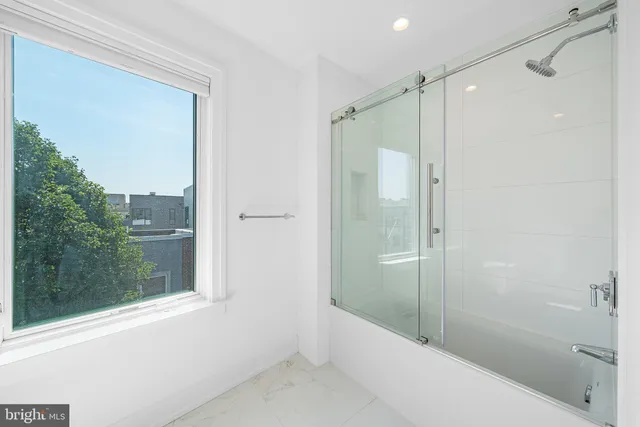 a view of an empty room with wooden floor and kitchen