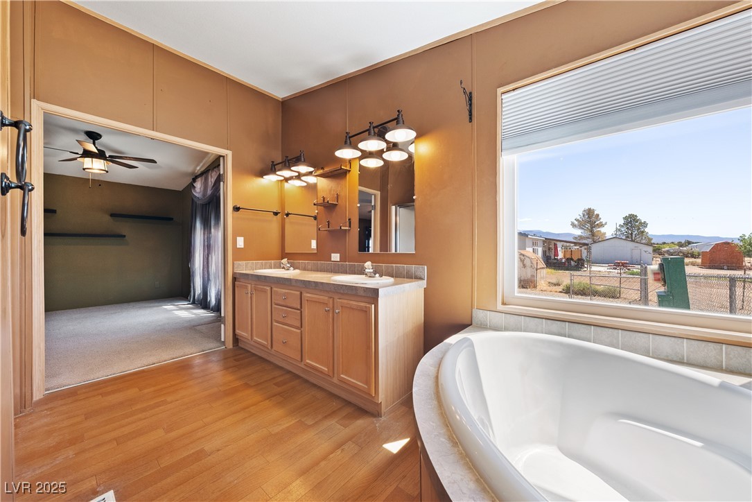 1391 East Casey Road Pahrump, NV 89048 - Photo 27 of 40 Full bathroom with healthy amount of natural light, a garden tub, wood finished floors, and double vanity