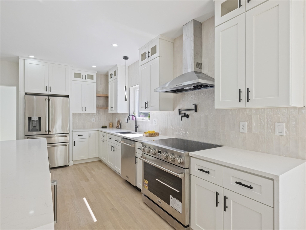 10 Ames Street Wakefield, MA 01880 - Photo 17 of 42 a kitchen with stainless steel appliances granite countertop a sink stove refrigerator and white cabinets with wooden floor