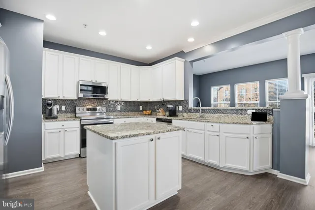 a kitchen with granite countertop white cabinets sink and stainless steel appliances