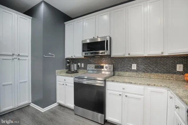 a kitchen with granite countertop white cabinets and white appliances