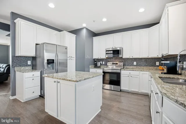 a kitchen with kitchen island granite countertop white cabinets and white appliances
