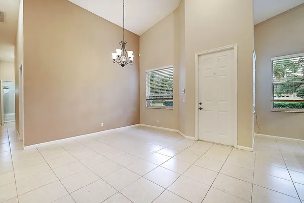a view of an empty room with window and chandelier fan