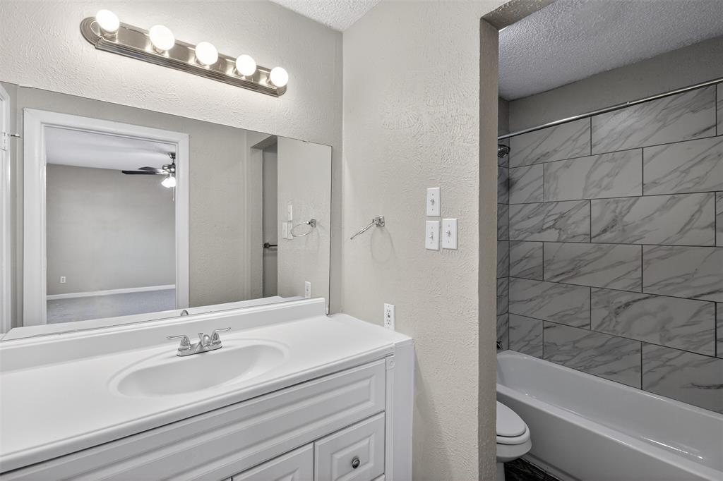 701 Harrison Lane Hurst, TX 76053 - Photo 19 of 29 a bathroom with a granite countertop bathtub shower sink vanity and toilet