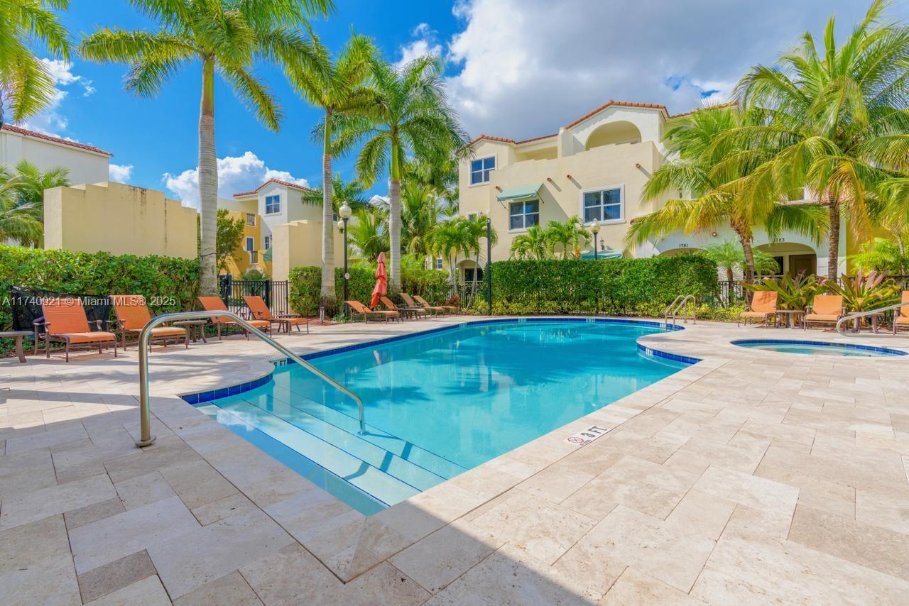 1799 Northwest 124th Way, Unit 1799 Pembroke Pines, FL 33028 - Photo 6 of 40 a view of a swimming pool with a lawn chairs under an umbrella