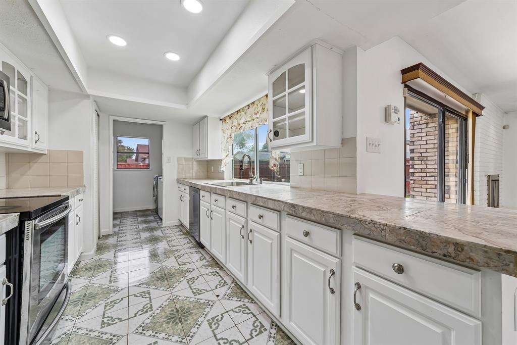 10239 Green Ash Road Dallas, TX 75243 - Photo 20 of 36 Kitchen featuring white cabinetry, light-toned countertops, a tile backsplash, and patterned floor tiles