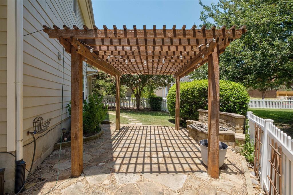2730 Kinney Oaks Court Austin, TX 78704 - Photo 27 of 32 A sturdy wooden pergola shades the stone patio adjacent to a green backyard.