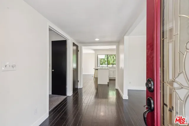 a kitchen with stainless steel appliances a sink a stove a refrigerator cabinets and a dining table with wooden floor