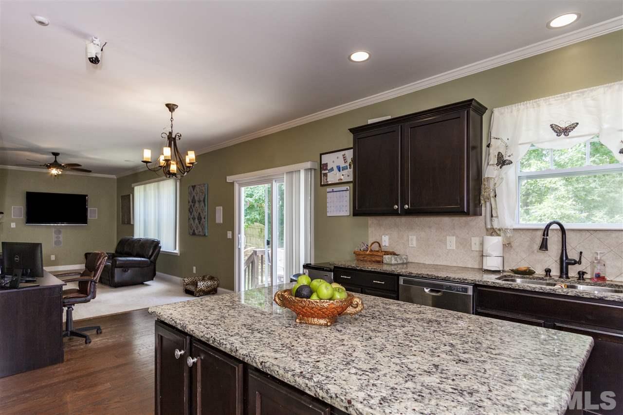 5607 Spring Glen Lane Raleigh, NC 27616 - Photo 5 of 21 a kitchen with kitchen island granite countertop a sink stove and cabinets