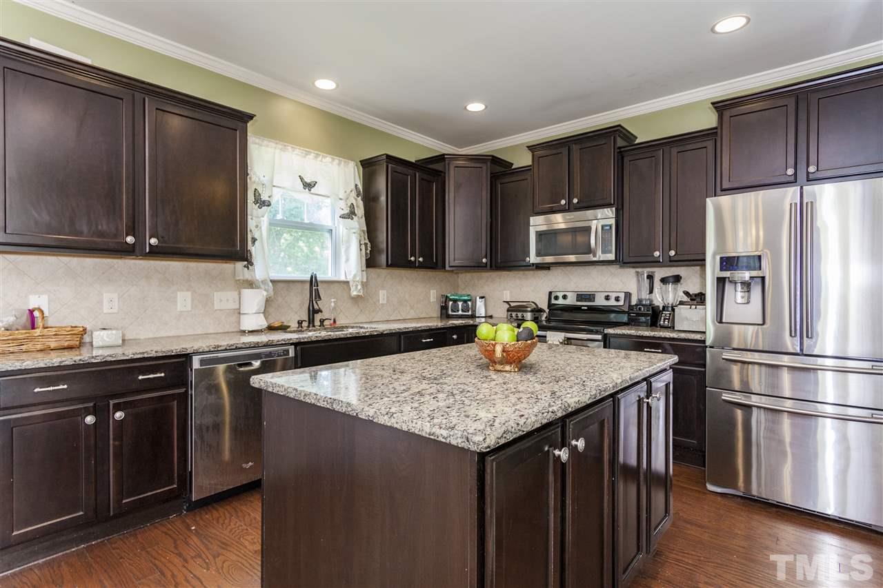 5607 Spring Glen Lane Raleigh, NC 27616 - Photo 6 of 21 a kitchen with stainless steel appliances granite countertop a sink stove microwave refrigerator and wooden cabinets
