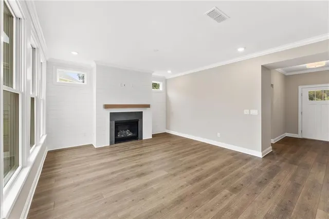 a view of a hallway with wooden floor and a bathroom