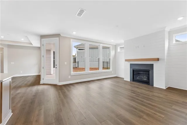a view of a kitchen with kitchen island wooden floors and stainless steel appliances