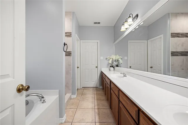 a spacious bathroom with a tub sink and mirror