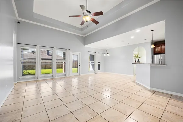 a view of an empty room with a window and kitchen view