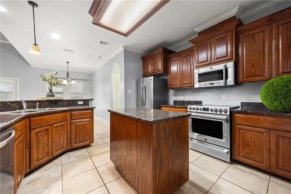 a kitchen with stainless steel appliances granite countertop wooden cabinets a stove top oven a sink and dishwasher