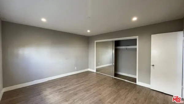 an empty room with wooden floor & closet area
