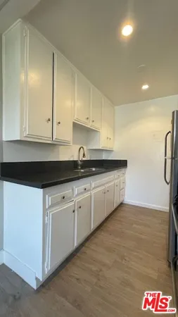 a white kitchen with granite countertop white cabinets and sink