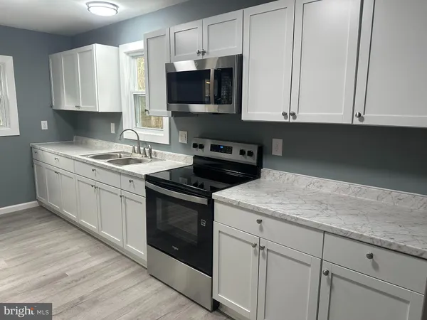 a kitchen with stainless steel appliances granite countertop white cabinets granite counter tops and a hard wood floors