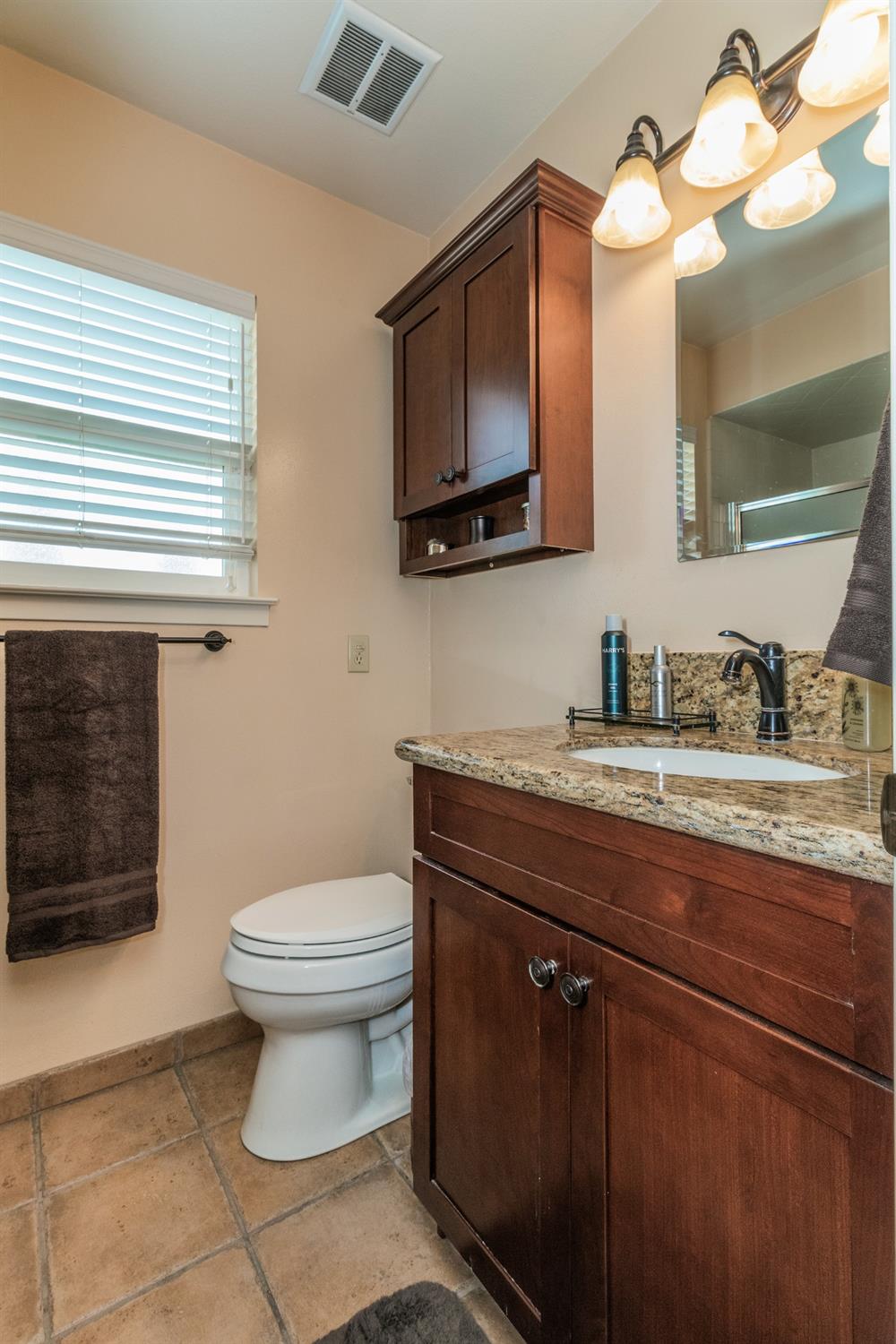 6233 South Armstrong Avenue Fowler, CA 93625 - Photo 22 of 30 a bathroom with a toilet a sink and a mirror