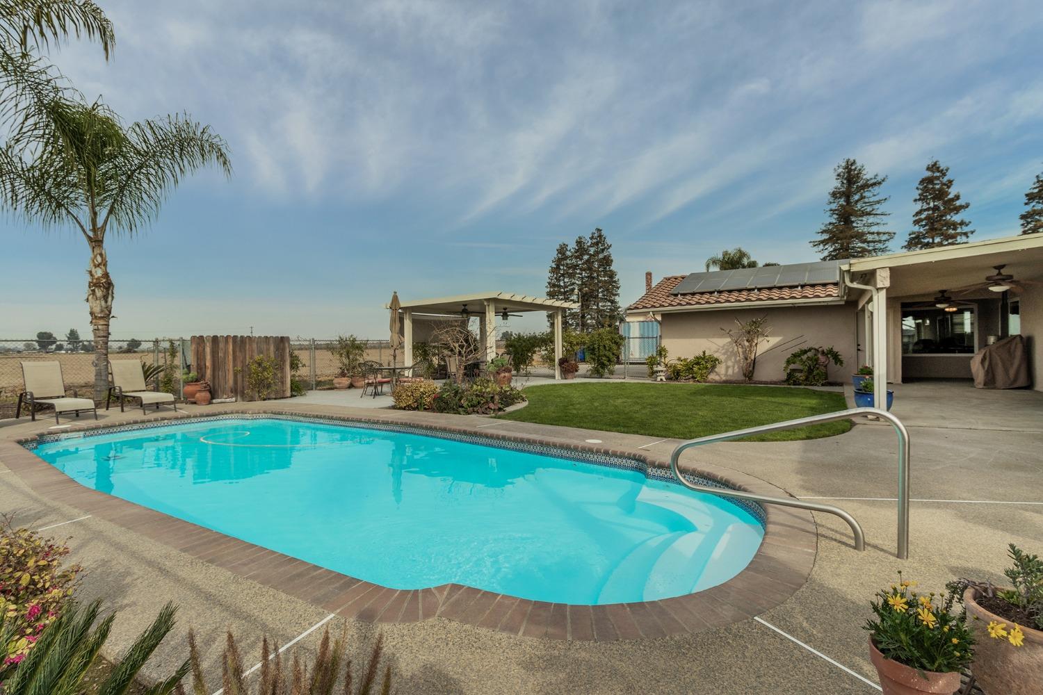 6233 South Armstrong Avenue Fowler, CA 93625 - Photo 25 of 30 a view of a swimming pool with a table and chairs under an umbrella