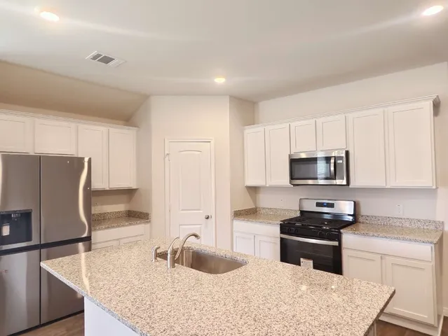 a kitchen with stainless steel appliances granite countertop a sink stove and refrigerator