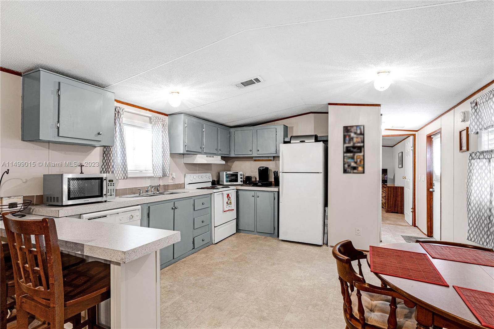 35250 Southwest 177th Court, Unit 77 Homestead, FL 33034 - Photo 11 of 30 a kitchen with a refrigerator a stove top oven a sink dishwasher and white cabinets