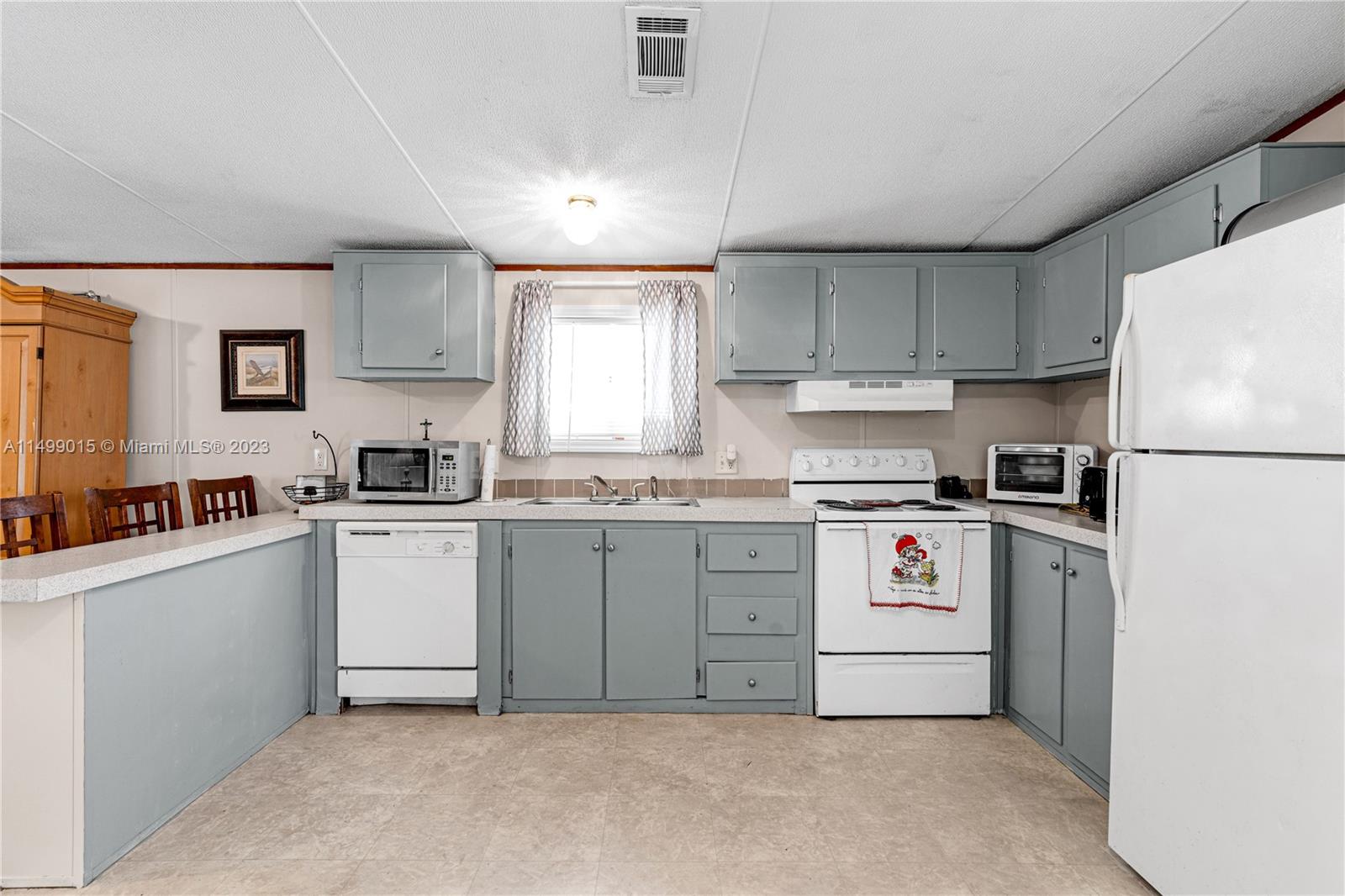 35250 Southwest 177th Court, Unit 77 Homestead, FL 33034 - Photo 12 of 30 a kitchen with granite countertop a refrigerator sink stove and cabinets