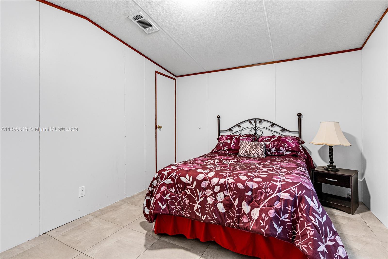 35250 Southwest 177th Court, Unit 77 Homestead, FL 33034 - Photo 24 of 30 a bedroom with a bed and a chandelier