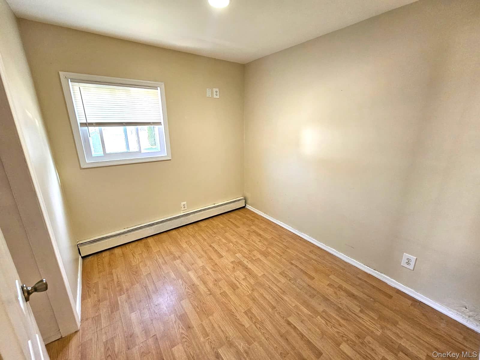 56 Applegate Drive Central Islip, NY 11722 - Photo 8 of 33 an empty room with wooden floor and windows
