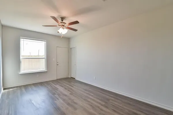 an empty room with wooden floor fan and windows