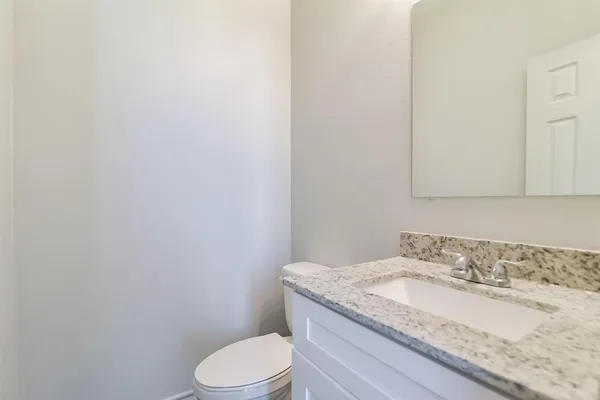 a bathroom with a granite countertop toilet sink and mirror