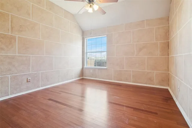 a view of a room with wooden floor and a ceiling fan