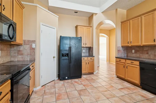 a kitchen with stainless steel appliances granite countertop a refrigerator a stove and a sink with wooden cabinets