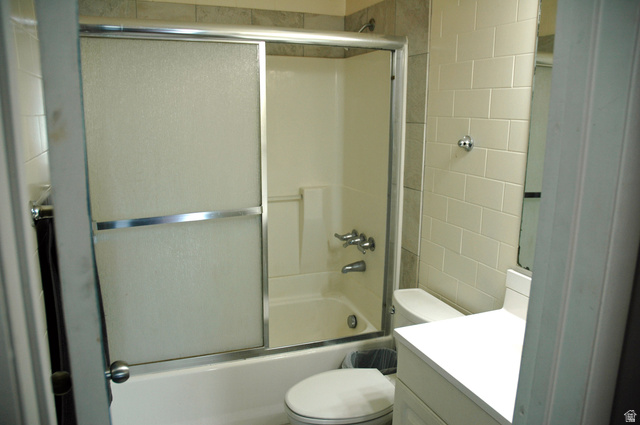 46 Lester Avenue, Unit G 24 Murray, UT 84107 - Photo 15 of 16 Full bathroom featuring a white vanity with a white countertop, subway-tiled walls, and a shower-over-tub combination with sliding glass doors