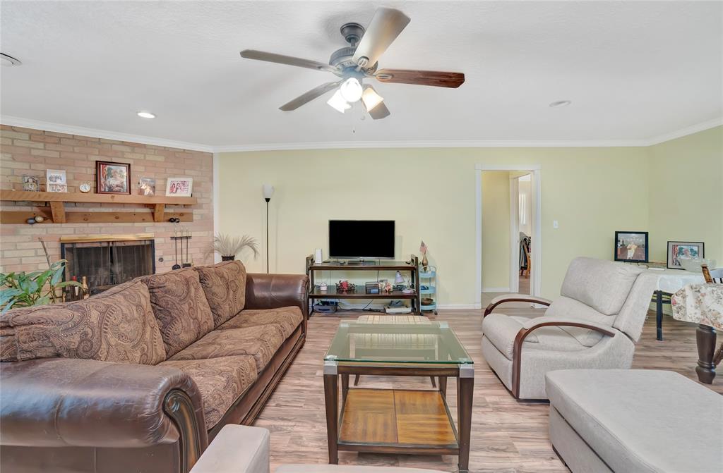 6021 Sycamore Creek Road Edgecliff Village, TX 76134 - Photo 11 of 37 Living room featuring light wood-type flooring, ornamental molding, a ceiling fan, baseboards, and a fireplace