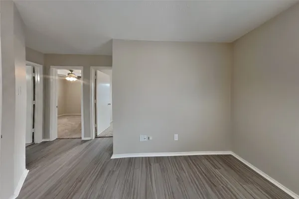 a view of an empty room with wooden floor and closet