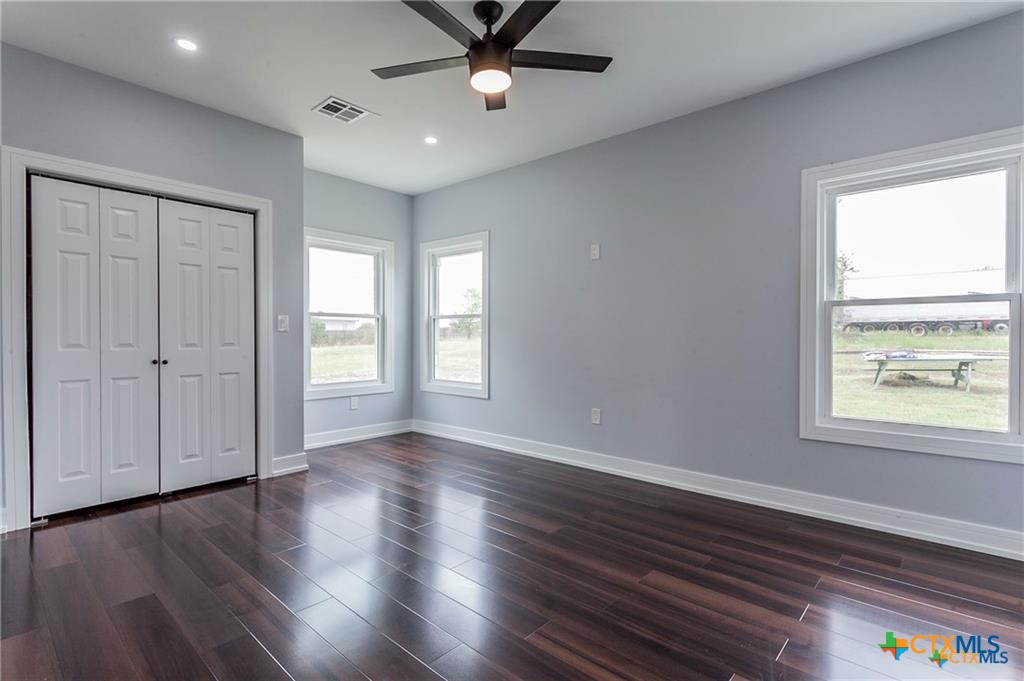 1110 North 42nd Street Temple, TX 76501 - Photo 21 of 32 an empty room with wooden floor chandelier fan and windows