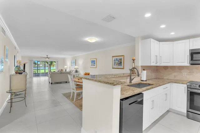 a kitchen with a sink white cabinets and chairs