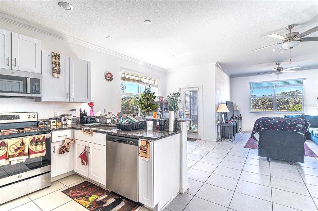 7014 Ripple Pond Loop Zephyrhills, FL 33541 - Photo 3 of 40 a kitchen with stainless steel appliances kitchen island granite countertop a stove a sink and a refrigerator