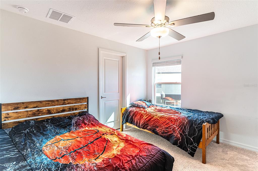 7014 Ripple Pond Loop Zephyrhills, FL 33541 - Photo 10 of 40 a bedroom with two beds and a chandelier