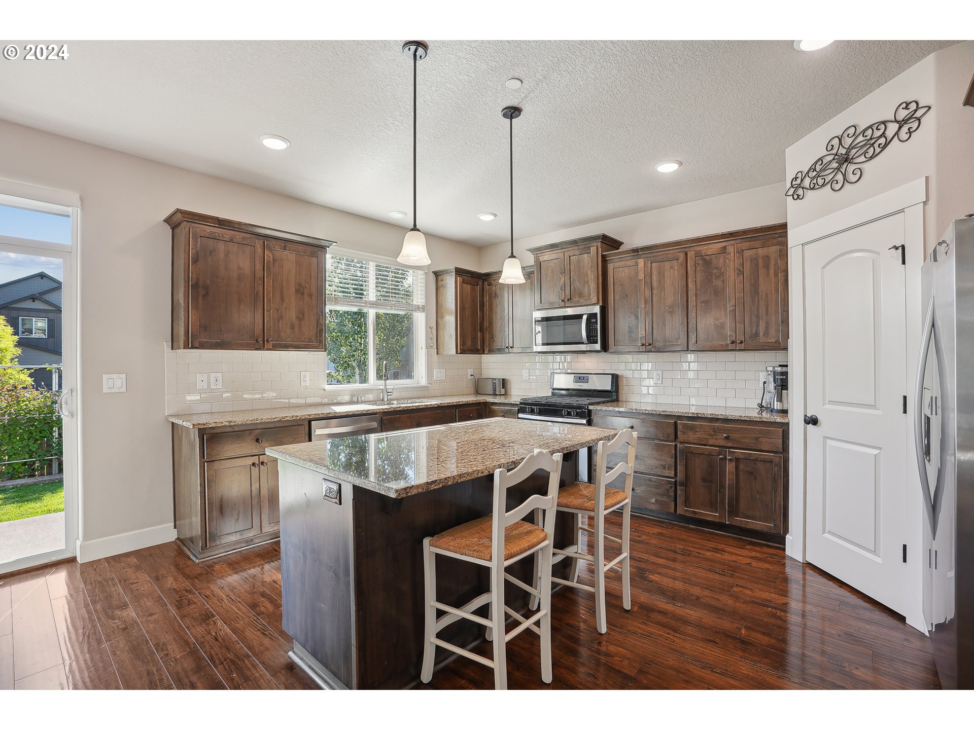 3520 Northeast Spruce Drive Camas, WA 98607 - Photo 14 of 38 a kitchen with kitchen island granite countertop wooden floors and white cabinets