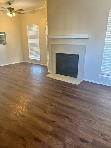 an empty room with wooden floor fireplace and windows