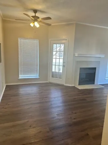 a view of an empty room with wooden floor fireplace and a window