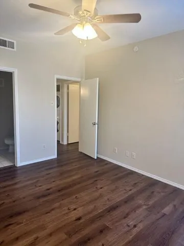 an empty room with wooden floor closet and windows