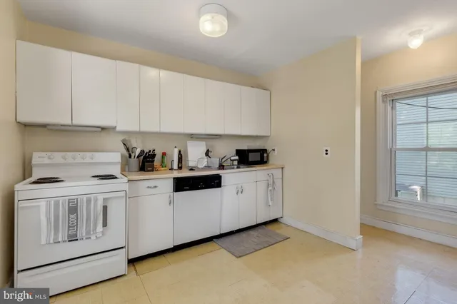 a kitchen with white cabinets and white appliances
