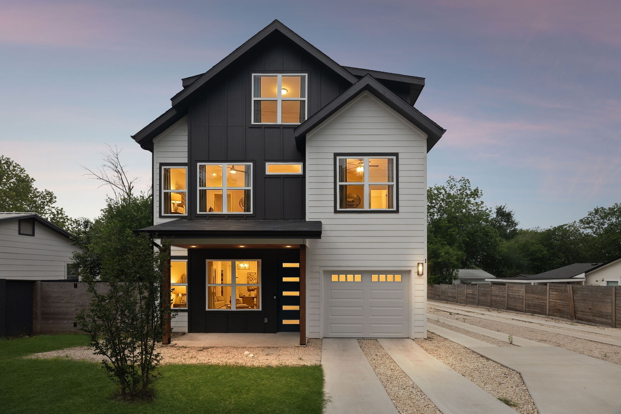 5305 Ledesma Road, Unit 1 Austin, TX 78721 - Photo 1 of 26 A striking front-facing view of the modern two-story home. The facade features a high-contrast design with white horizontal siding and dark charcoal board-and-batten accents. A covered front porch with natural wood pillars leads to a contemporary glass-paneled door, while a single-car garage and drought-tolerant gravel landscaping complete the curb appeal.