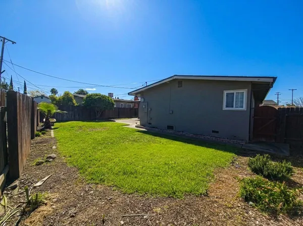 a backyard of a house with plants and wooden fence